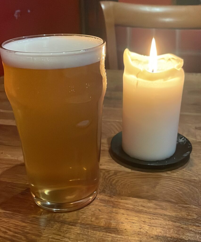 Image of a pint of beer with a burning candle next to it on a solo traveling trip